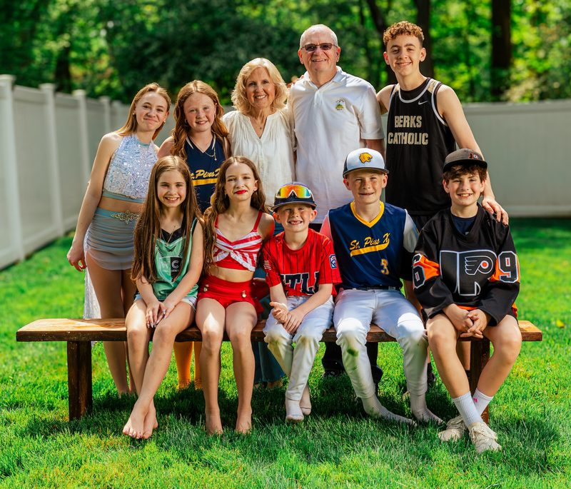 Large extended family gathered on and around a bench for a summer group portrait