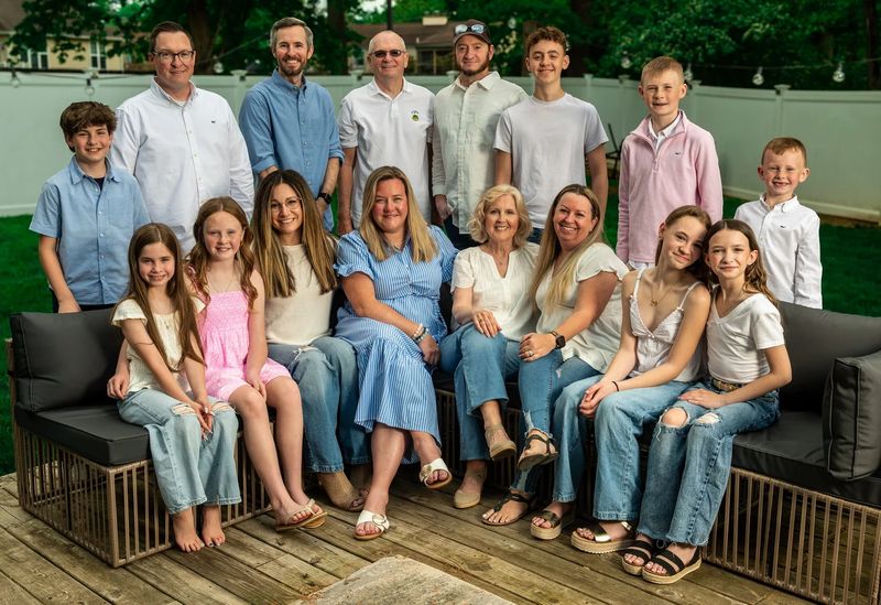 Large extended family of sixteen gathered on backyard patio furniture for a relaxed group portrait in Philadelphia
