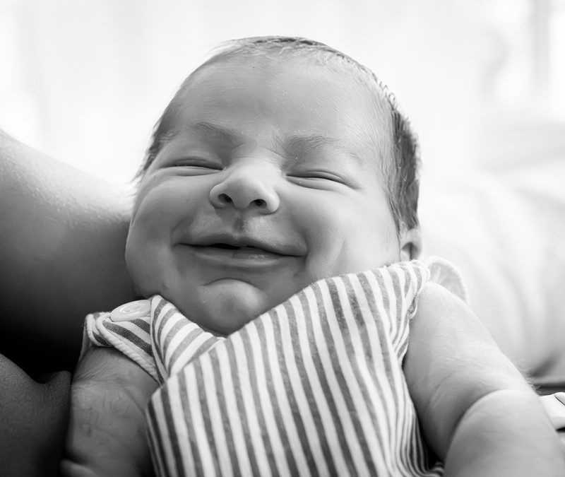 Black-and-white close-up of a newborn baby smiling in her sleep